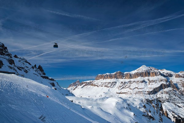 View of a ski resort piste with people skiing in Dolomites in Italy with cable car ski lift. Ski area Arabba. Arabba