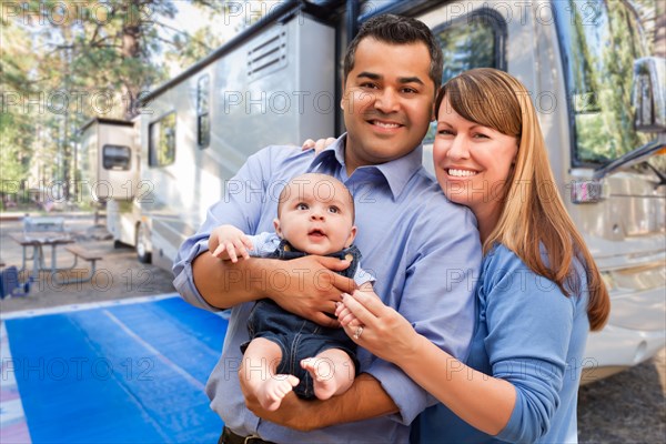 mixed-race family in front of their beautiful RV at the campground