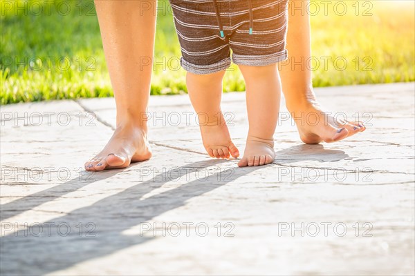 Mother and baby feet taking steps outdoors