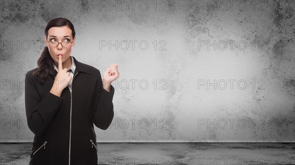 Young adult woman looking to the side standing in front of blank grungy blank wall with copy space