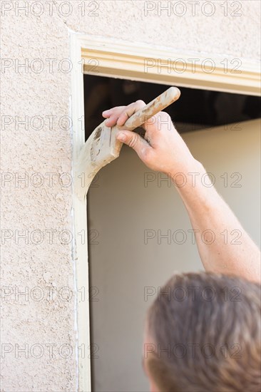 Professional painter cutting in with A brush to paint house door frame