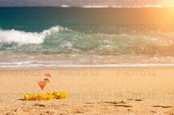 Tropical drink and lei on a sandy beach shoreline