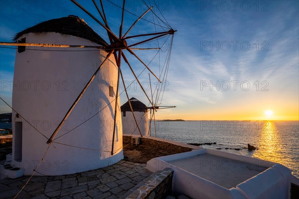 Scenic view of famous Mykonos town windmills Traditional greek windmills on Mykonos island on sunset with dramatic sky
