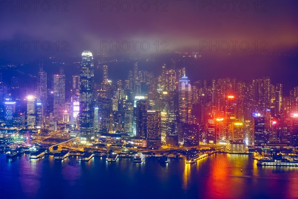 Aerial view of illuminated Hong Kong skyline cityscape downtown skyscrapers over Victoria Harbour in the evening. Hong Kong