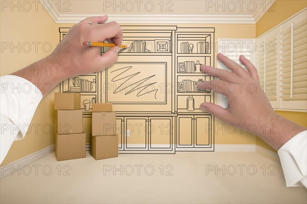 Hands drawing beautiful entertainment unit in room with moving boxes