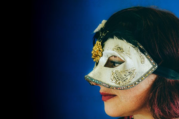 Portrait of a caucasian red head adult woman wearing a venetian theater mask