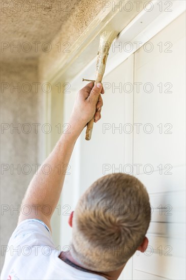 Professional painter cutting in with A brush to paint garage door frame