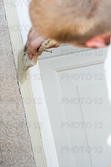 Professional painter cutting in with A brush to paint garage door frame