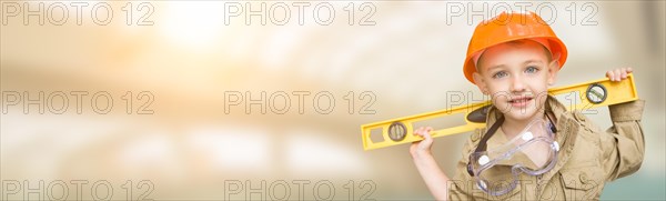 Cute young boy dressed as contractor holding level wide banner with room for text