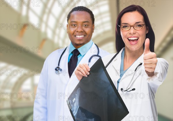 Female and male caucasian and african american doctors in hospital office with x-ray film and thumbs up