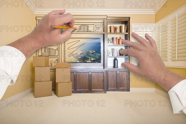 Hands drawing beautiful entertainment unit in room with moving boxes