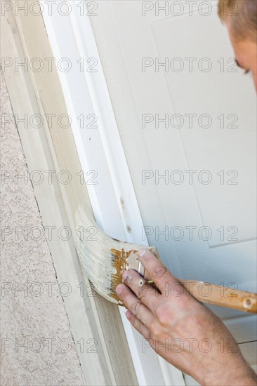 Professional painter cutting in with A brush to paint garage door frame