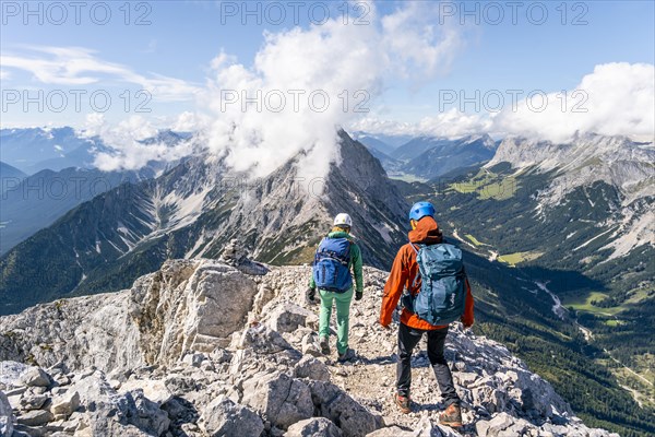 Hiker with climbing helmet on a steep rocky ridge