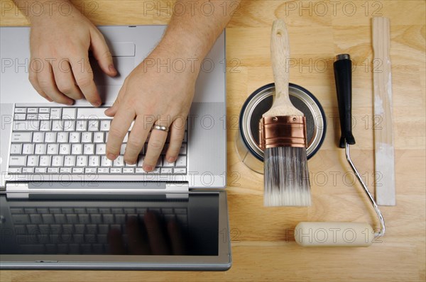 Handyman researches on laptop with paint brush