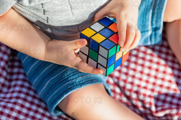Baby boy sitting on picnic blanket playing with Rubki's Cube