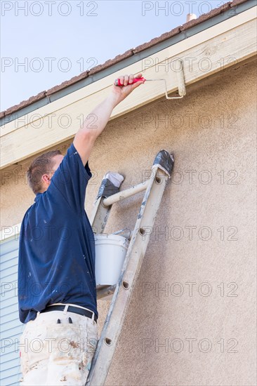 Professional painter using A small roller to paint house fascia