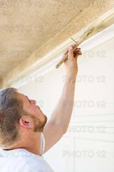 Professional painter cutting in with A brush to paint garage door frame