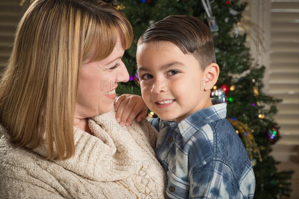 Happy mother and mixed-race son hug near their christmas tree