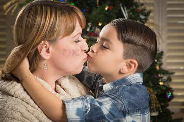 Happy mother and mixed-race son hug near their christmas tree