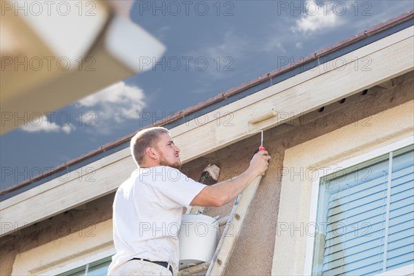 Professional painter using A small roller to paint house fascia