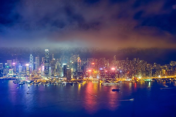 Aerial view of illuminated Hong Kong skyline cityscape downtown skyscrapers over Victoria Harbour in the evening. Hong Kong