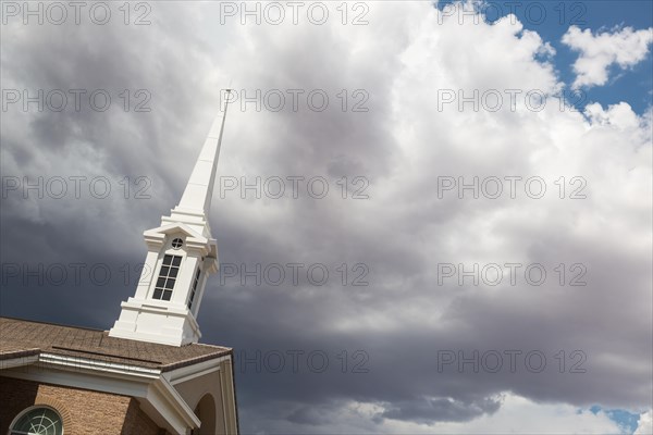 Church steeple tower below ominous stormy thunderstorm clouds