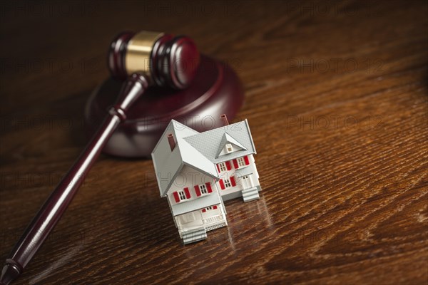 Gavel and small model house on wooden table