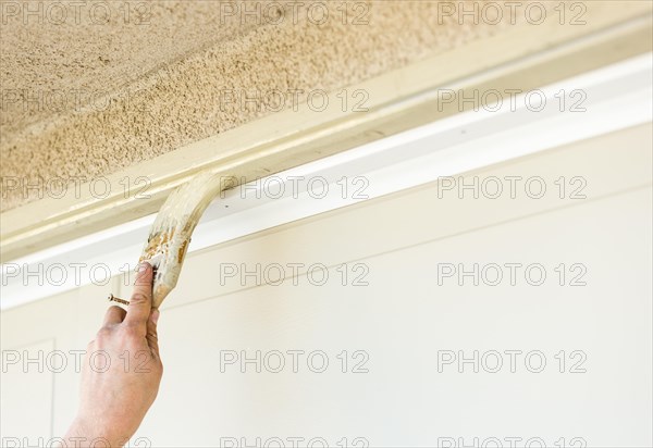 Professional painter cutting in with A brush to paint garage door frame