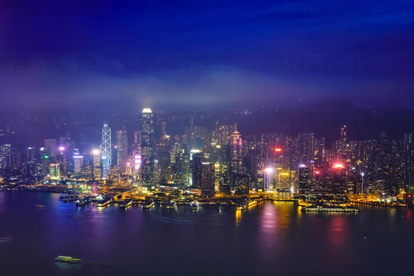 Aerial view of illuminated Hong Kong skyline cityscape downtown skyscrapers over Victoria Harbour in the evening. Hong Kong