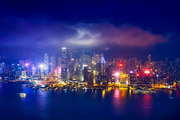 Aerial view of illuminated Hong Kong skyline cityscape downtown skyscrapers over Victoria Harbour in the evening. Hong Kong