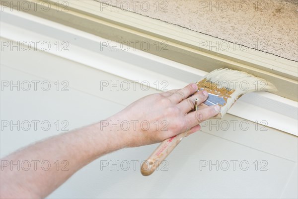 Professional painter cutting in with A brush to paint garage door frame