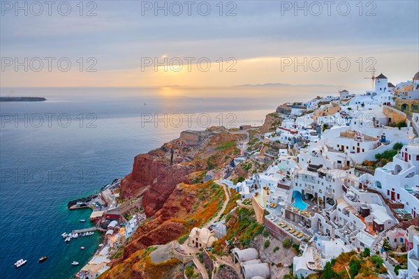 Famous greek iconic selfie spot tourist destination Oia village with traditional white houses and windmills in Santorini island on sunset in twilight