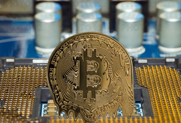 A melting Bitcoin stands on a motherboard