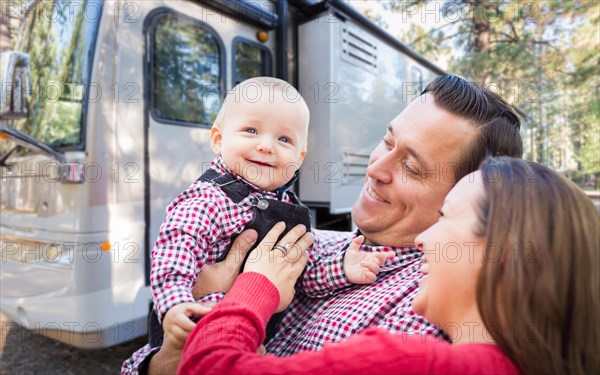 Happy young caucasian family in front of their beautiful RV at the campground