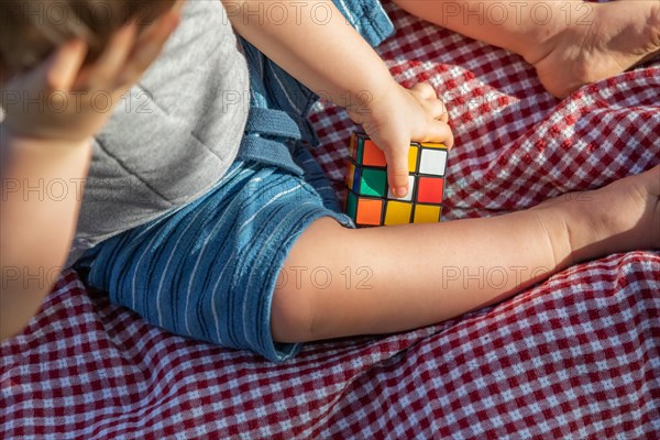 Baby boy sitting on picnic blanket playing with Rubki's Cube