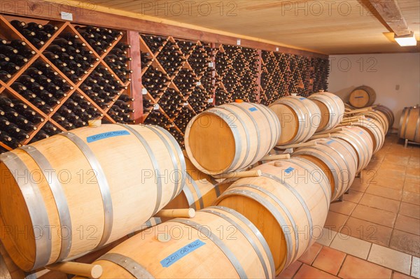 Wine barrels and bottles age inside dark cellar