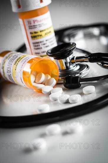 Non-Proprietary medicine prescription bottles and spilled pills abstract with stethoscope