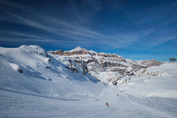 View of a ski resort piste with people skiing in Dolomites in Italy with cable car ski lift. Ski area Arabba. Arabba