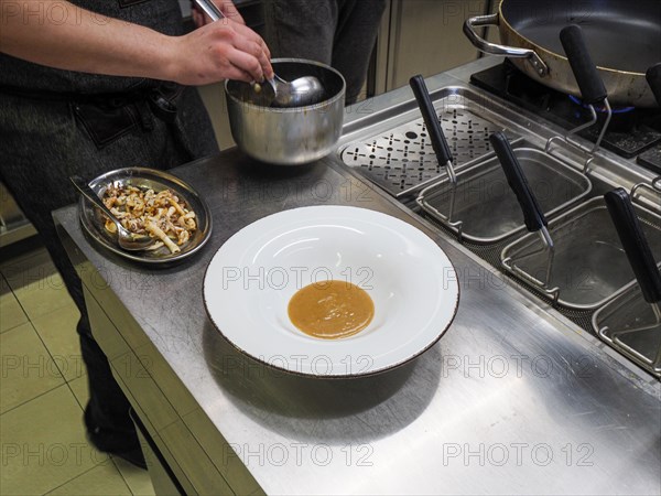 Chef plating pan cooked flambe atlantic squid with potato rich sauce cream reduction