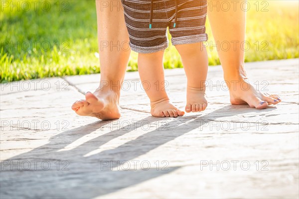 Mother and baby feet taking steps outdoors