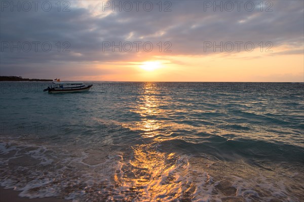 Calm ocean with boat during tropical sunrise