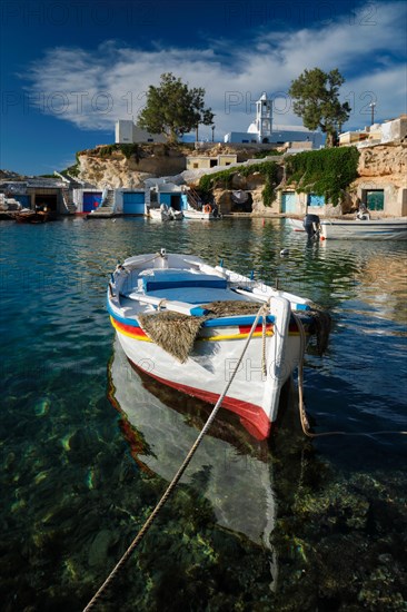 Fishing boats moored in crystal clear turquoise sea water in harbour in Greek fishing village of Mandrakia