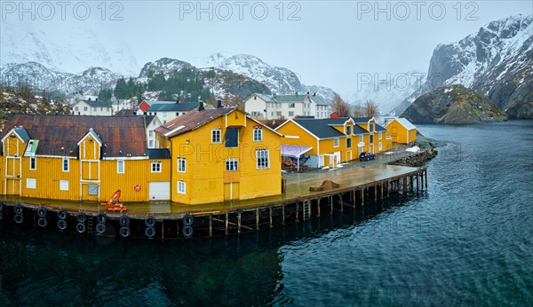 Panorama of Nusfjord authentic fishing village with yellow rorbu houses in Norwegian fjord in winter. Lofoten islands