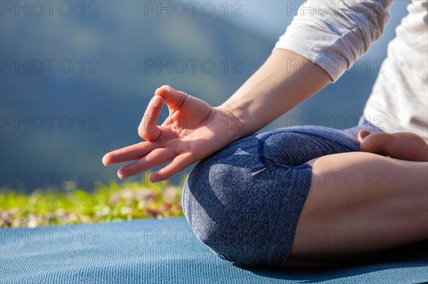 Close up of woman in Padmasana yoga lotus pose with chin mudra outdoors with copyspace