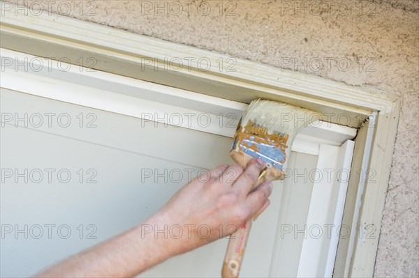 Professional painter cutting in with A brush to paint garage door frame