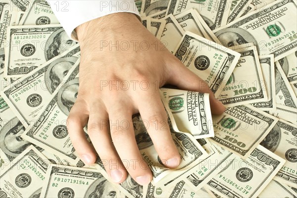 Greedy hand grabs money lot of dollars