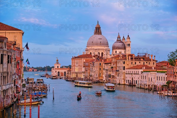 Panorama of Venice Grand Canal with gondola boats and Santa Maria della Salute church on sunset from Ponte dell'Accademia bridge. Venice