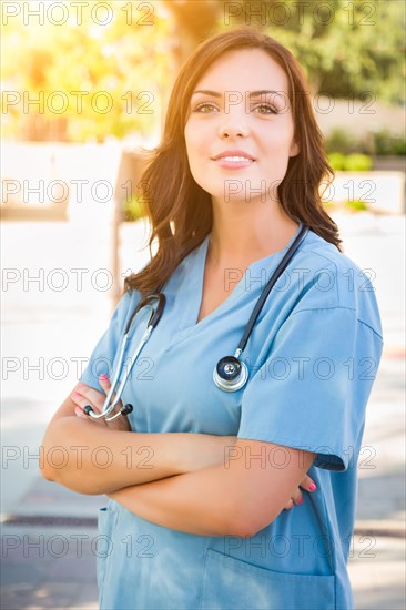 Portrait of young adult female doctor or nurse wearing scrubs and stethoscope outside