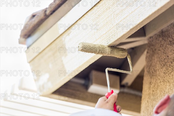 Professional painter using A small roller to paint house fascia