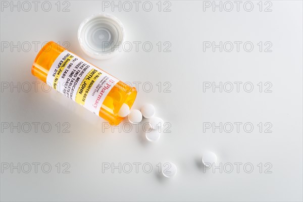 Non-Proprietary medicine prescription bottle and spilled pills over head on grey background